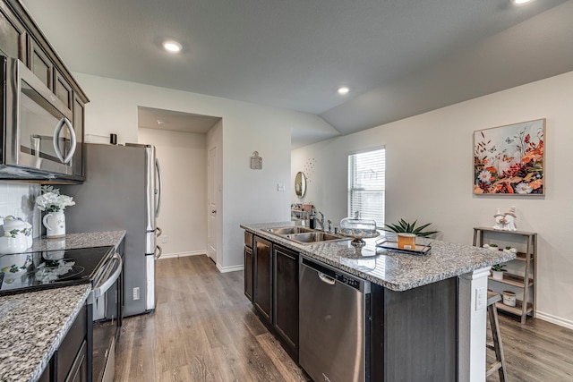 kitchen featuring dark brown cabinetry, sink, lofted ceiling, an island with sink, and hardwood / wood-style flooring