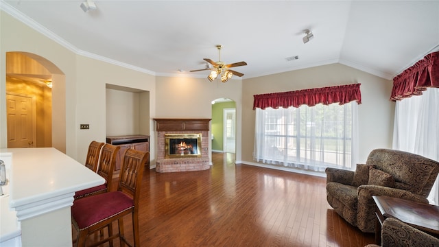 living room featuring ornamental molding, lofted ceiling, a fireplace, and dark wood-type flooring