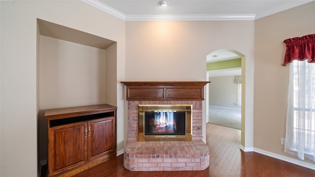 unfurnished living room with ornamental molding, a brick fireplace, and dark hardwood / wood-style floors