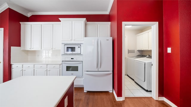 kitchen featuring separate washer and dryer, light wood-type flooring, white appliances, and white cabinetry