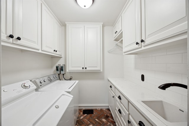 clothes washing area featuring independent washer and dryer, cabinets, and sink