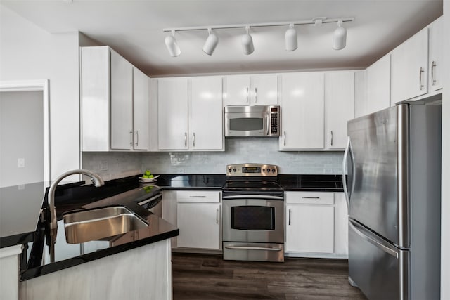 kitchen featuring sink, dark hardwood / wood-style flooring, white cabinetry, appliances with stainless steel finishes, and backsplash