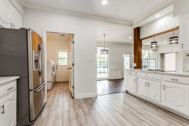 kitchen featuring a healthy amount of sunlight, stainless steel refrigerator with ice dispenser, separate washer and dryer, and white cabinetry