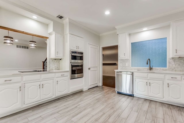 kitchen with stainless steel appliances, hanging light fixtures, white cabinets, and light hardwood / wood-style flooring