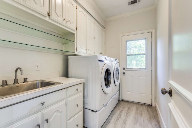 laundry area featuring sink, light hardwood / wood-style flooring, cabinets, separate washer and dryer, and crown molding