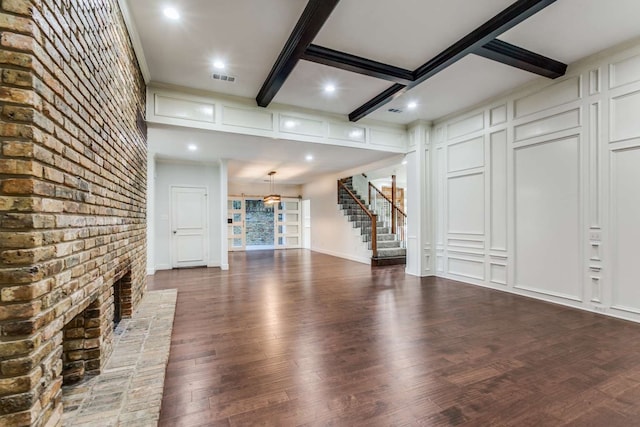 unfurnished living room with a fireplace, dark hardwood / wood-style floors, and beamed ceiling