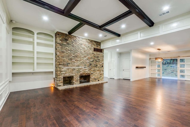 unfurnished living room with a brick fireplace, dark hardwood / wood-style floors, brick wall, and beam ceiling