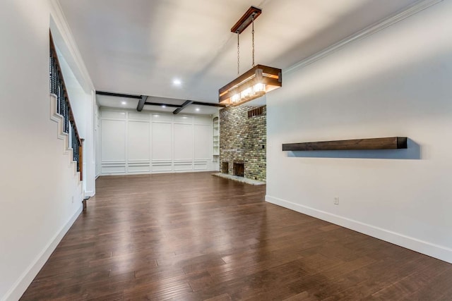 unfurnished living room featuring brick wall, ornamental molding, a fireplace, and dark hardwood / wood-style flooring