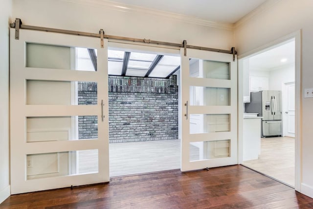 entryway featuring a barn door, crown molding, and hardwood / wood-style flooring