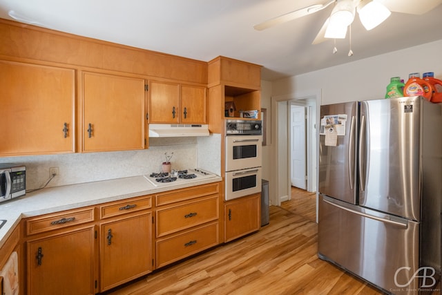 kitchen featuring ceiling fan, stainless steel appliances, light wood-type flooring, and decorative backsplash