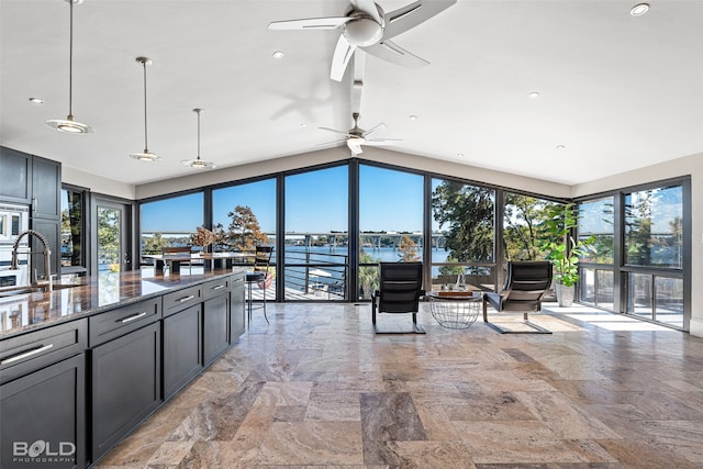 kitchen featuring a water view, dark stone counters, plenty of natural light, and pendant lighting