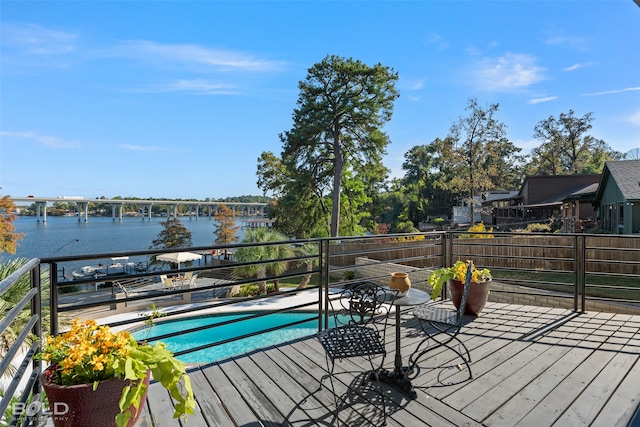 wooden deck with a water view and a fenced in pool