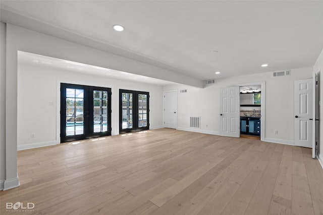 unfurnished living room featuring french doors and light hardwood / wood-style floors