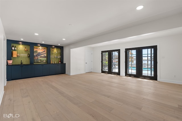 unfurnished living room featuring sink, french doors, and light hardwood / wood-style flooring