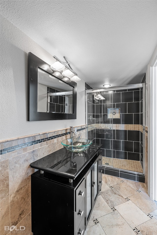 bathroom with vanity, a textured ceiling, tile walls, and tiled shower