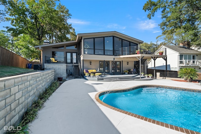 rear view of house featuring french doors, a patio area, and a fenced in pool