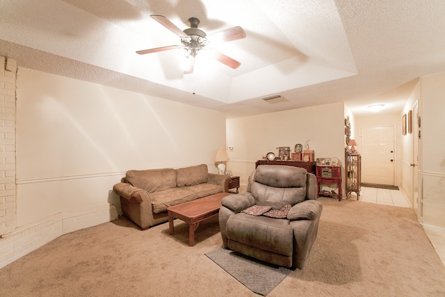 carpeted living room with ceiling fan, a tray ceiling, and a textured ceiling