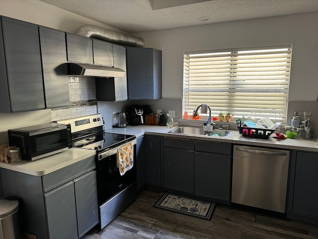 kitchen with stainless steel appliances, gray cabinetry, dark wood-type flooring, sink, and a textured ceiling