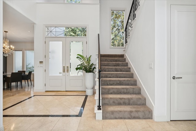 tiled entrance foyer with french doors and a notable chandelier