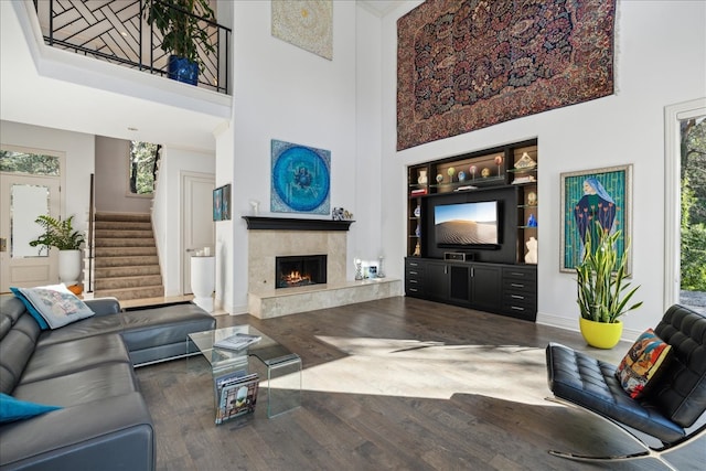 living room featuring wood-type flooring, a high ceiling, and a high end fireplace