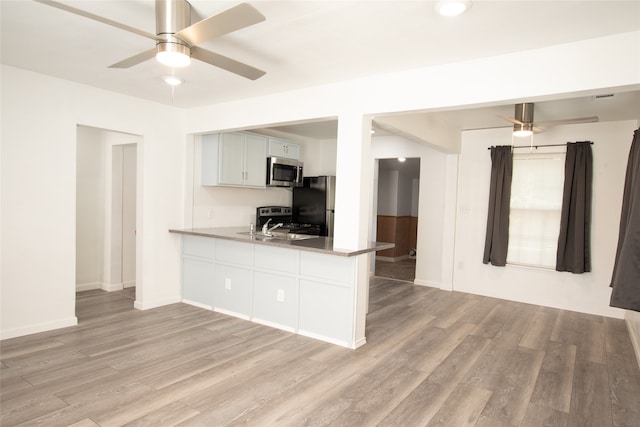 kitchen featuring kitchen peninsula, stainless steel appliances, ceiling fan, and light hardwood / wood-style floors