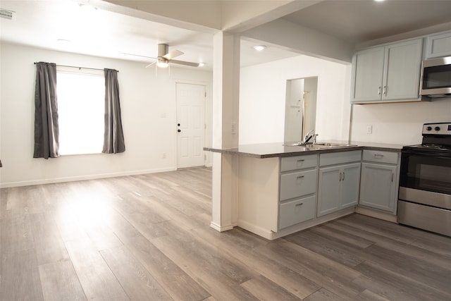 kitchen featuring kitchen peninsula, appliances with stainless steel finishes, ceiling fan, sink, and wood-type flooring