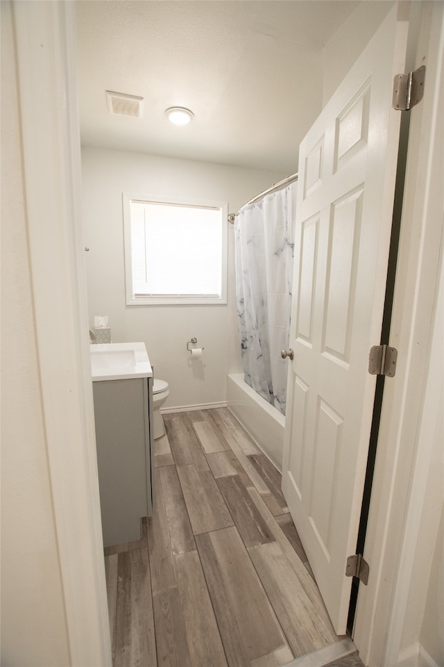 full bathroom featuring hardwood / wood-style floors, vanity, toilet, and shower / tub combo with curtain