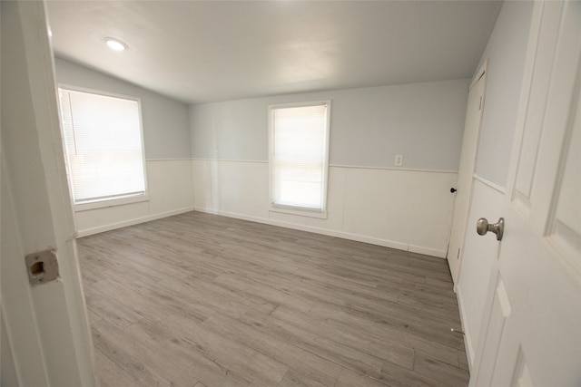 spare room with vaulted ceiling and hardwood / wood-style flooring