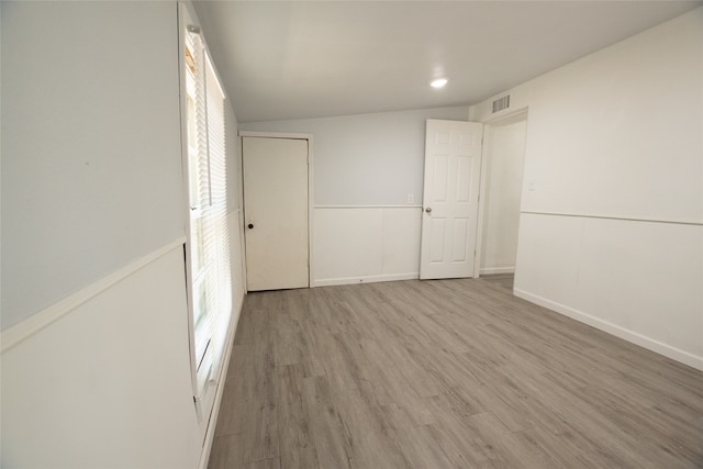 unfurnished bedroom with lofted ceiling and hardwood / wood-style flooring