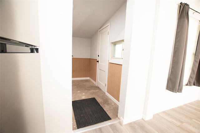 hall with light wood-type flooring and wooden walls