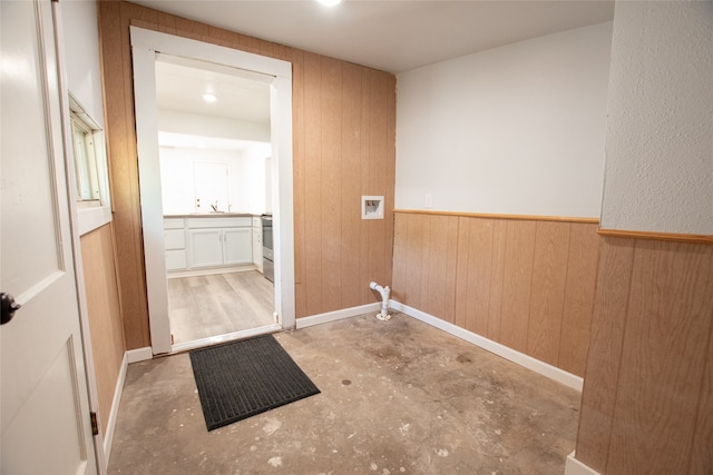 clothes washing area with hookup for a washing machine, wooden walls, and sink