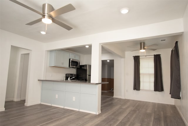 kitchen with hardwood / wood-style flooring, ceiling fan, light stone countertops, and appliances with stainless steel finishes