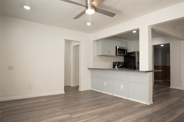 kitchen featuring hardwood / wood-style flooring, ceiling fan, appliances with stainless steel finishes, stone countertops, and kitchen peninsula