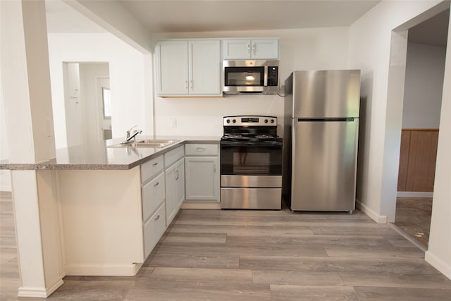 kitchen featuring kitchen peninsula, white cabinetry, stainless steel appliances, and light wood-type flooring