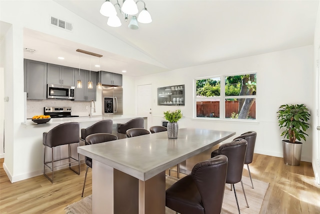 dining space with light hardwood / wood-style flooring, lofted ceiling, and an inviting chandelier