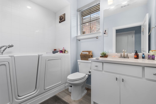 bathroom with a tub to relax in, hardwood / wood-style flooring, vanity, and toilet