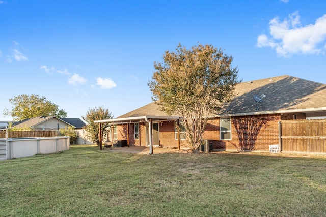 rear view of property with a patio, a yard, and central AC unit