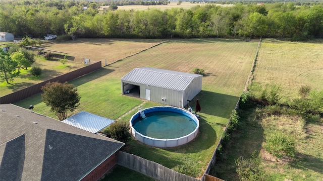 view of pool with a yard, an outbuilding, and a rural view