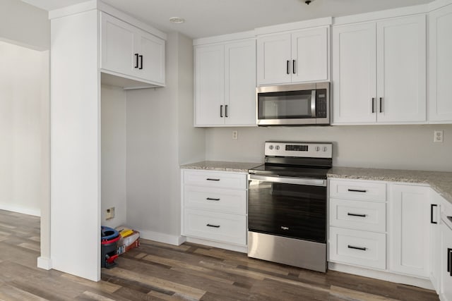 kitchen with white cabinets, light stone counters, stainless steel appliances, and dark hardwood / wood-style flooring