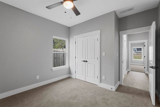 unfurnished bedroom featuring ceiling fan, a closet, and light carpet