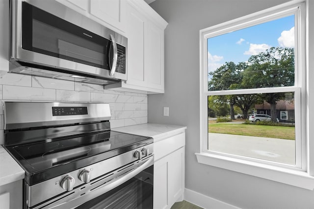 kitchen featuring decorative backsplash, light stone countertops, white cabinets, and appliances with stainless steel finishes