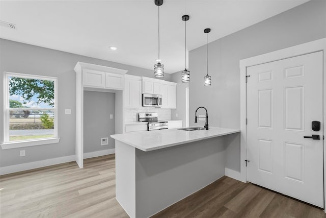 kitchen featuring white cabinets, sink, decorative light fixtures, stainless steel appliances, and light wood-type flooring