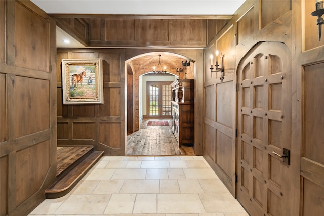 interior space with wood walls, french doors, and light tile patterned floors