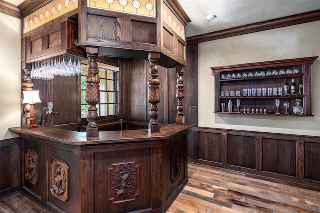 bar featuring crown molding, light hardwood / wood-style flooring, wooden walls, and dark brown cabinets