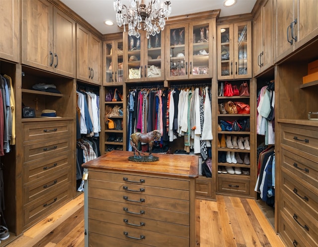 walk in closet with an inviting chandelier and light hardwood / wood-style flooring