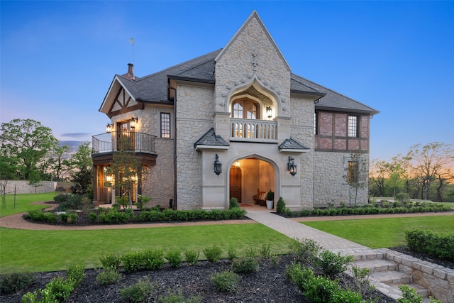 view of front facade featuring a balcony and a lawn