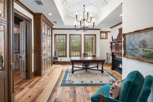 interior space with a raised ceiling, a notable chandelier, crown molding, and light hardwood / wood-style flooring