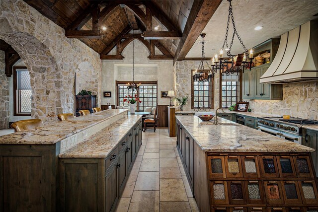 3801 Dugas Rd, Aubrey, TX 76227 - kitchen with a chandelier, premium range hood, double oven range, a spacious island, and stone tile flooring