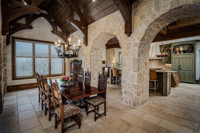 3801 Dugas Rd, Aubrey, TX 76227 - dining area featuring stone tile flooring, arched walkways, lofted ceiling with beams, and a chandelier