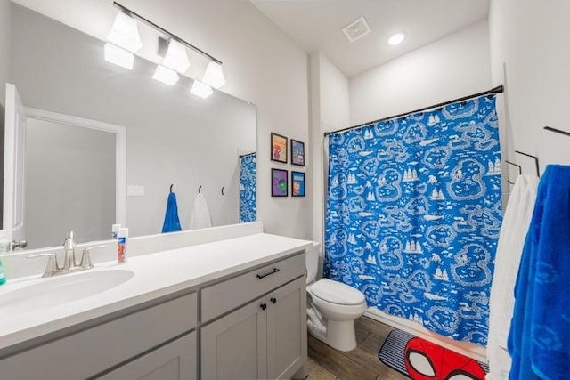 bathroom featuring wood-type flooring, vanity, walk in shower, and toilet